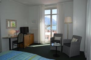 グラヴェドーナにあるホテル ラ ヴィラのベッドと椅子、窓が備わるホテルルームです。