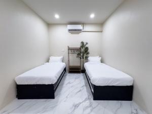 two beds in a room with white walls at Yolo House In Narathiwat in Kampong Botong