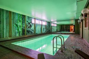 a swimming pool in a building with a mural at Hotell Kung Gösta by First in Mora