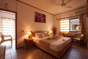 a bedroom with a bed and two chairs and two windows at Orchid Self Catering Apartment in La Digue