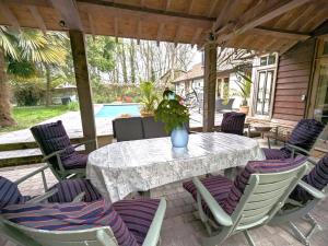 a table and chairs with a vase on a patio at Rural Studio with Shared Pool, Large Gardens & Tennis, Dog Friendly! Chichester Holiday Properties in Chichester
