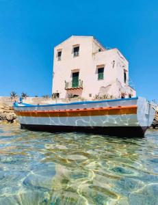a boat sitting in the water next to a building at Guest House Lo specchio sul mare in Santa Flavia +16 photos