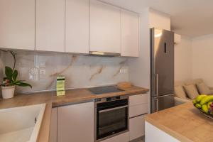 a kitchen with white cabinets and a stainless steel refrigerator at Christina's Apartment in Afantou