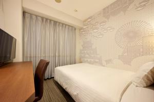 a hotel room with a bed and a desk and a television at Via Inn Shin Osaka in Osaka