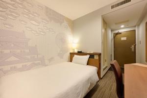 a hotel room with a bed and a desk and a door at Via Inn Shin Osaka in Osaka
