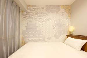 a bedroom with a white bed and a wall at Via Inn Shin Osaka in Osaka