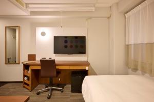 a room with a desk with a computer and a television at Via Inn Shin Osaka in Osaka