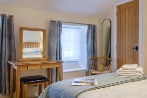a bedroom with a bed and a mirror and a chair at Corner House in Ambleside