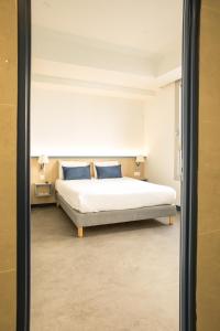 a bedroom with a bed with two blue pillows at Kyriad Villefranche Sur Saone Porte du Beaujolais -Rénové- in Villefranche-sur-Saône