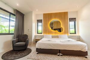 a bedroom with a bed and a chair and a mirror at Bangtao Beach Walk Villa by Taan Residence in Bang Tao Beach +8 photos