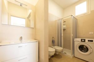 a bathroom with a toilet sink and a washing machine at Centonze appartamenti in San Foca +77 photos