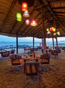 a beach restaurant with tables and chairs on the beach at The Park Visakhapatnam in Visakhapatnam