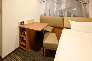 a hotel room with a bed and a desk and a bed at Via Inn Shin Osaka in Osaka