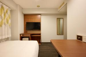 a hotel room with a bed and a desk at Via Inn Shin Osaka in Osaka