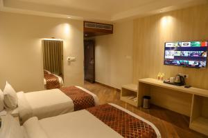 a hotel room with two beds and a flat screen tv at Four Leaf Hotel Arjuna Manor, Varanasi in Varanasi