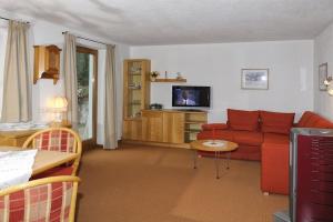 salon z czerwoną kanapą i telewizorem w obiekcie Appartementhaus St. Martin w mieście Seefeld in Tirol