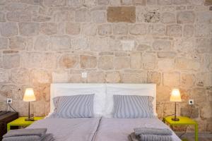 a bedroom with a stone wall with a bed and two lamps at Apartments Martinis in Vis