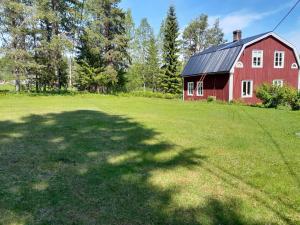 a red barn in a field with a large shadow at Grynberget in Grynberget