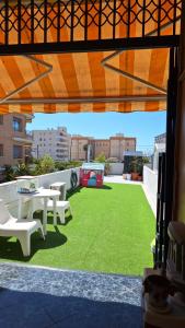 a patio with a table and chairs and grass at Apartamento con encanto in Torredembarra