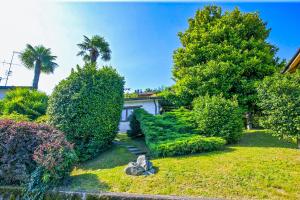 Un jardín con árboles y arbustos frente a una casa. en Casa La Campanella, en Germignaga