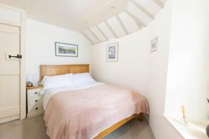 a white bedroom with a bed and a window at The Bakehouse in Port Isaac