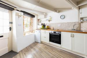 a kitchen with white cabinets and a black oven at The Bakehouse in Port Isaac