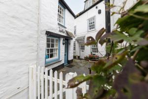 a white house with a blue door and a fence at The Bakehouse in Port Isaac