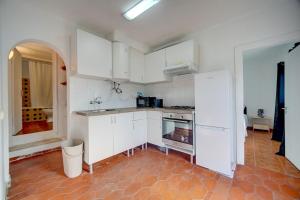 a kitchen with white cabinets and a red tile floor at Murches' House in Alcabideche