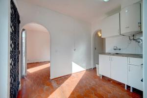 a kitchen with white cabinets and a red tile floor at Murches' House in Alcabideche