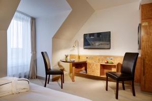デュッセルドルフにあるLindner Hotel Dusseldorf Airport, part of JdV by Hyattのデスクと椅子2脚が備わるホテルルームです。