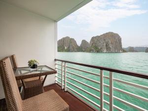 a balcony with a table and chairs overlooking the water at Amanda Premier Cruise in Ha Long