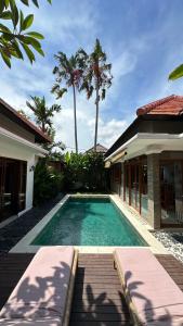 a swimming pool next to a house with palm trees at Villa Searenity Seminyak in Seminyak