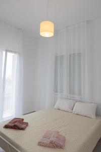 a white bedroom with a bed with two towels on it at Alexas country house in Kamena Vourla