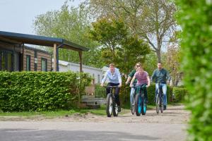 three people riding bikes down a dirt road at Siblu Camping de Oase in Renesse