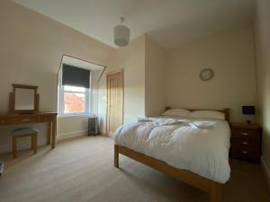 a bedroom with a bed and a dresser and a window at Inverness Holiday House in Dalneigh