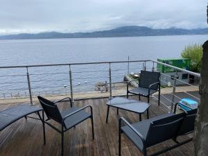 a deck with chairs and tables and a large body of water at Les Brises in Saint-Gingolph