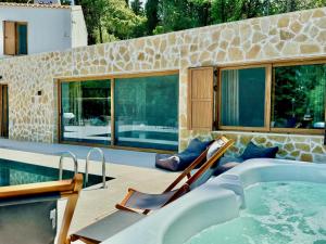 a swimming pool with two chairs and a tub at Domenico Morani Luxury Villa Concept with private pool by DadoVillas in Gastouri +44 photos
