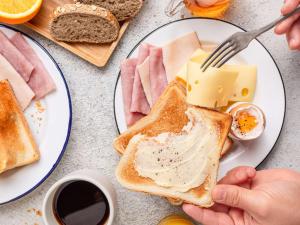 a person eating a breakfast of toast with butter and cheese at ibis budget Nice Californie Lenval in Nice