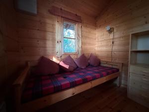 a bed in a log cabin with a window at Mönni saari in Savonlinna