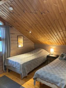 zwei Betten in einem Zimmer mit Holzdecken in der Unterkunft Latvahonka Cottage in Jämsä + 21 Fotos