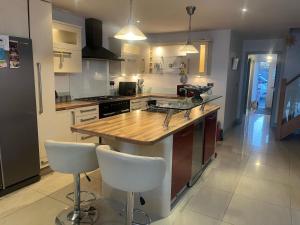 a kitchen with a wooden counter top and white chairs at Large Stunning Sea View Coastal Townhouse in Killough