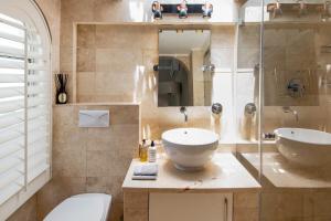 a bathroom with a sink and a toilet and a mirror at See Table Mountain from a Historic Home in Cape Town +31 photos