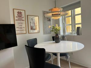 a white dining room table with chairs and a vase with flowers at Pakhuset, DownTownSkagen in Skagen