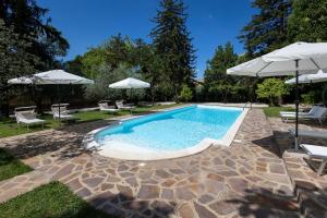 a swimming pool with two umbrellas and chairs at Il Cottage - Tenuta dell'Inviolata in Velletri