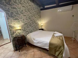 a bedroom with a bed and a stone wall at Il Cottage - Tenuta dell'Inviolata in Velletri