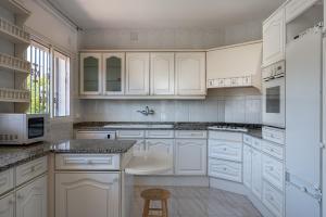 a white kitchen with white cabinets and a stool at AT166 Playa a 10 min a pie in Torredembarra