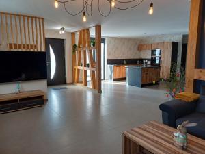 a living room with a large television and a kitchen at Gîtes Kymsourit - Sauna - SPA - proche Europa-Park et Rulantica - Centre Alsace in Sand +24 photos