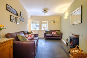 a living room with a leather couch and a fireplace at Victory Cottage in Ambleside