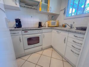 eine Küche mit weißen Schränken und einem Herd mit Backofen in der Unterkunft Maison avec jardin et parking, proche des plages in Fréjus