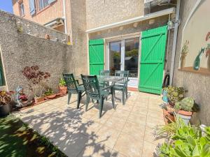 eine Terrasse mit grünen Türen sowie einem Tisch und Stühlen in der Unterkunft Maison avec jardin et parking, proche des plages in Fréjus